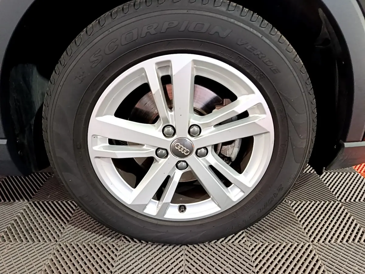 Gros plan sur la roue avant droite d’un Audi Q3 noir 35 TDI 150 S tronic avec jante argentée à 5 branches doubles.