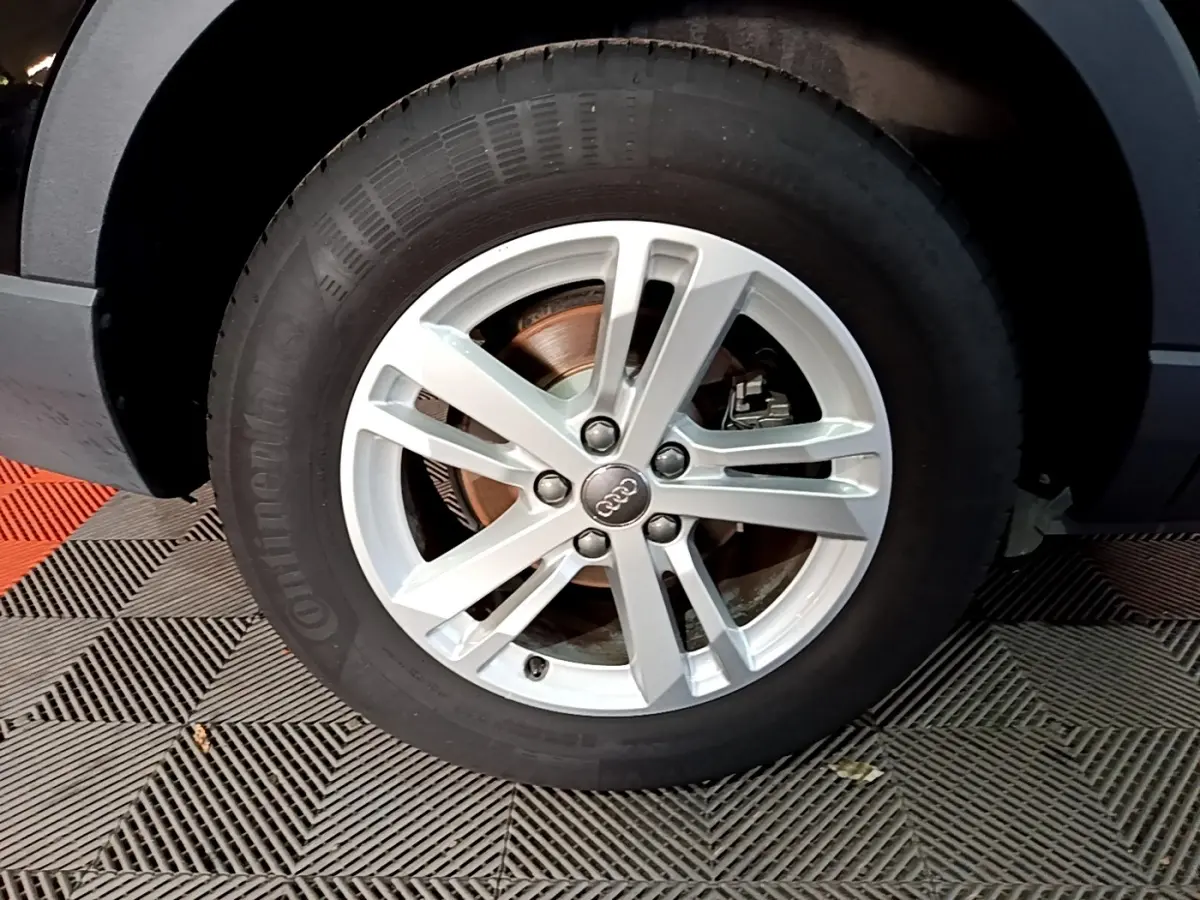 Gros plan sur la roue avant droite avec jante argentée de l'Audi Q3 noir 35 TDI 150 S Tronic Business Line.