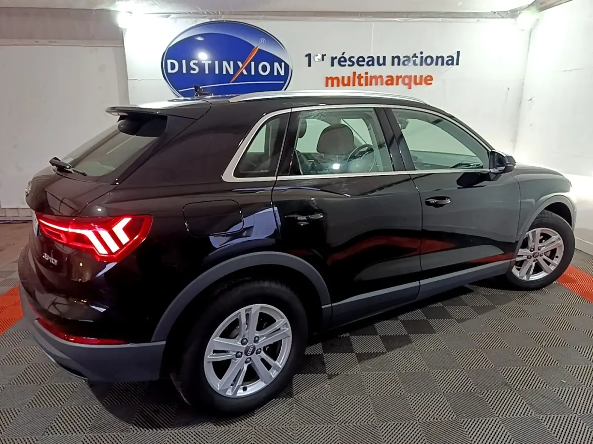 Audi Q3 35 TDI noir vue de profil côté droit en intérieur avec feux arrière allumés et jantes argentées.