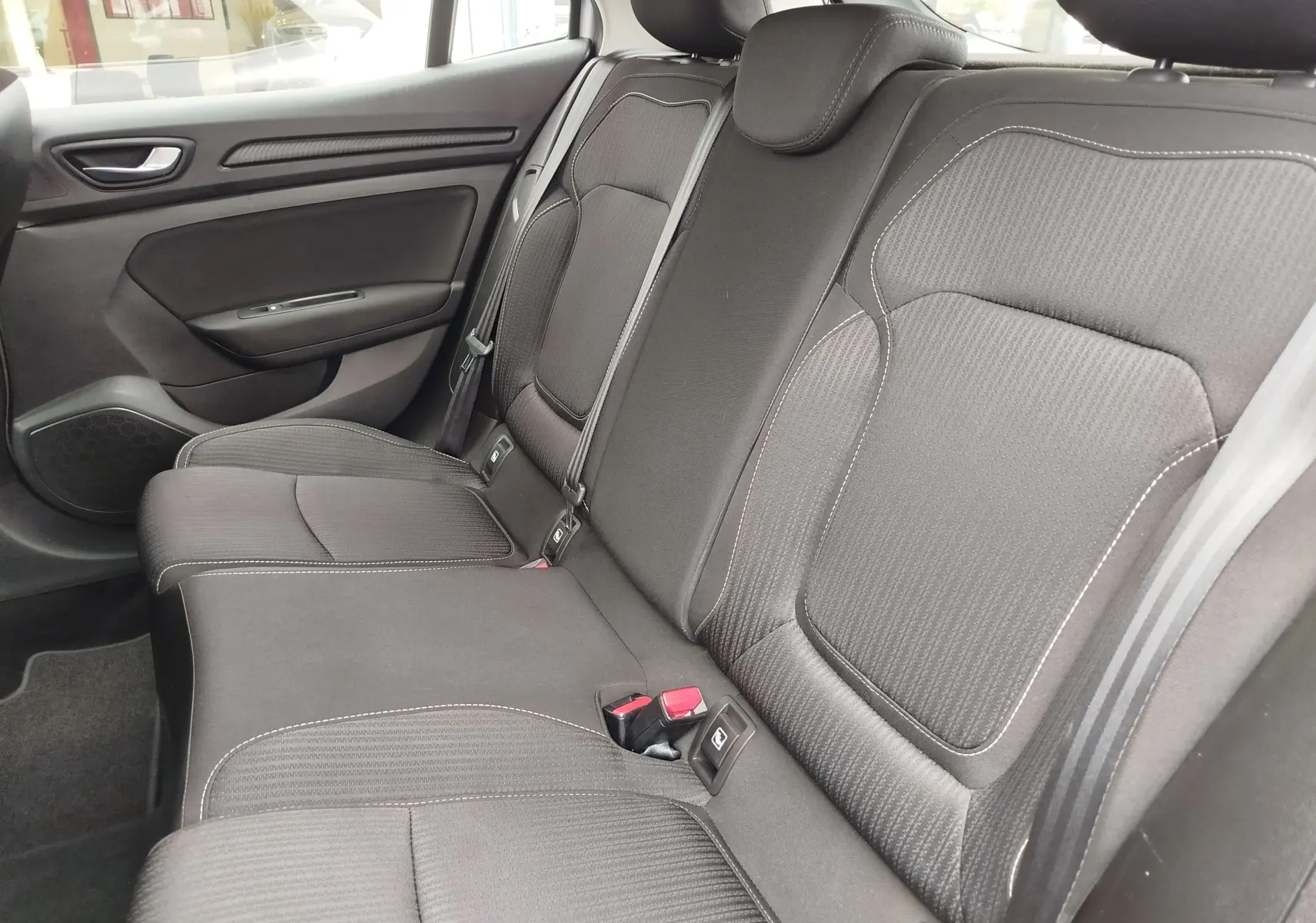 Vue intérieure côté droit des sièges arrière noirs avec surpiqûres blanches de la Renault Mégane gris Titanium 2018.
