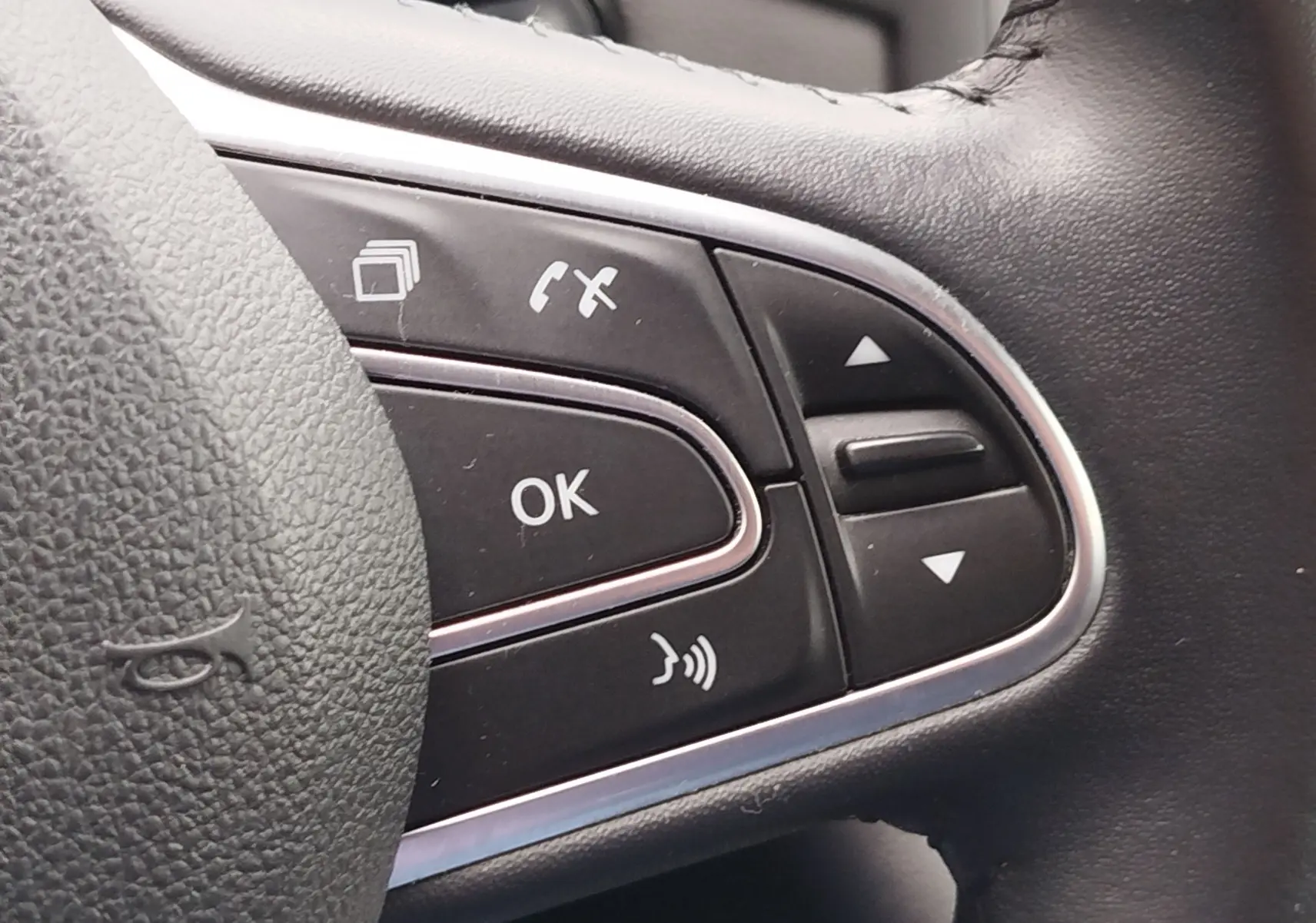 Gros plan sur les commandes multifonctions noires du volant en cuir de la Renault Mégane gris Titanium, version 2018.
