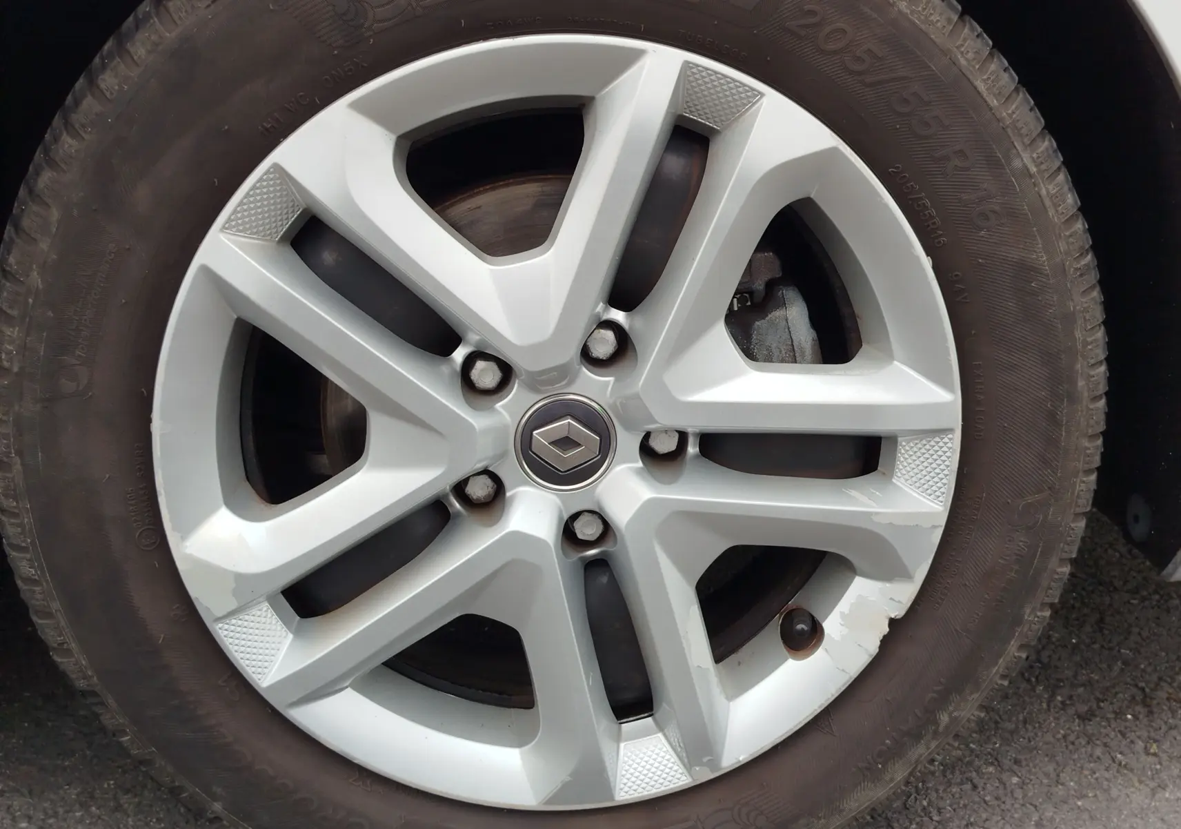 Gros plan sur la jante alliage argentée avec logo Renault au centre, montée sur un pneu Michelin d'une Renault Mégane gris titanium.