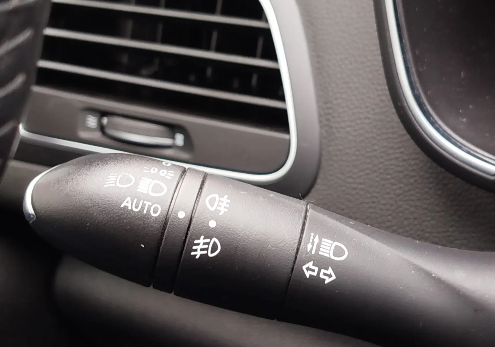 Gros plan sur la commande des phares et clignotants dans l’habitacle gris d’une Renault Mégane 1.5 dCi 2018.