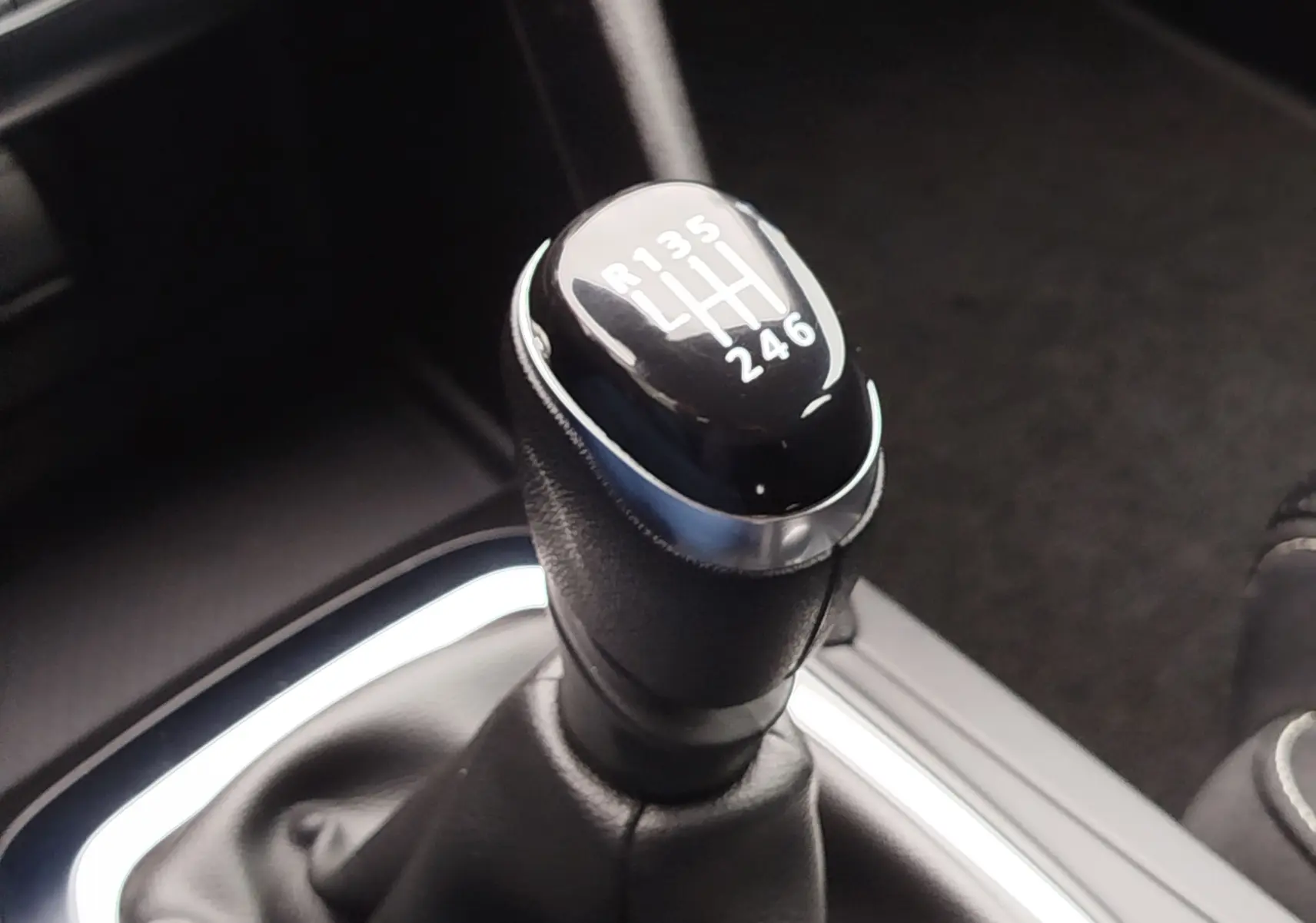 Gros plan sur le levier de vitesses manuel noir de la Renault Mégane 1.5 dCi, montrant les rapports gravés en blanc.