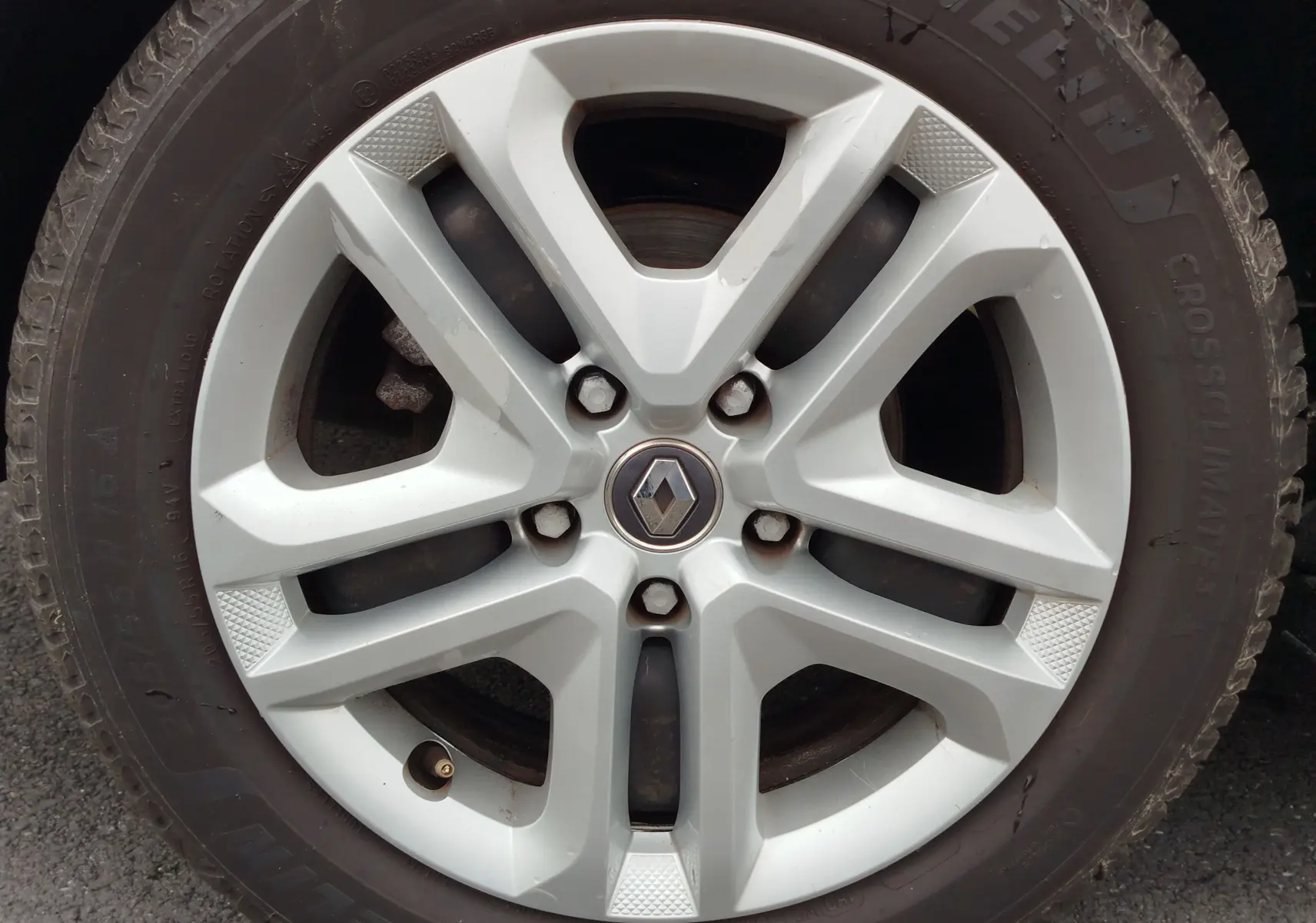 Gros plan sur la jante alliage argentée avec logo Renault au centre, montée sur pneu Michelin CrossClimate.