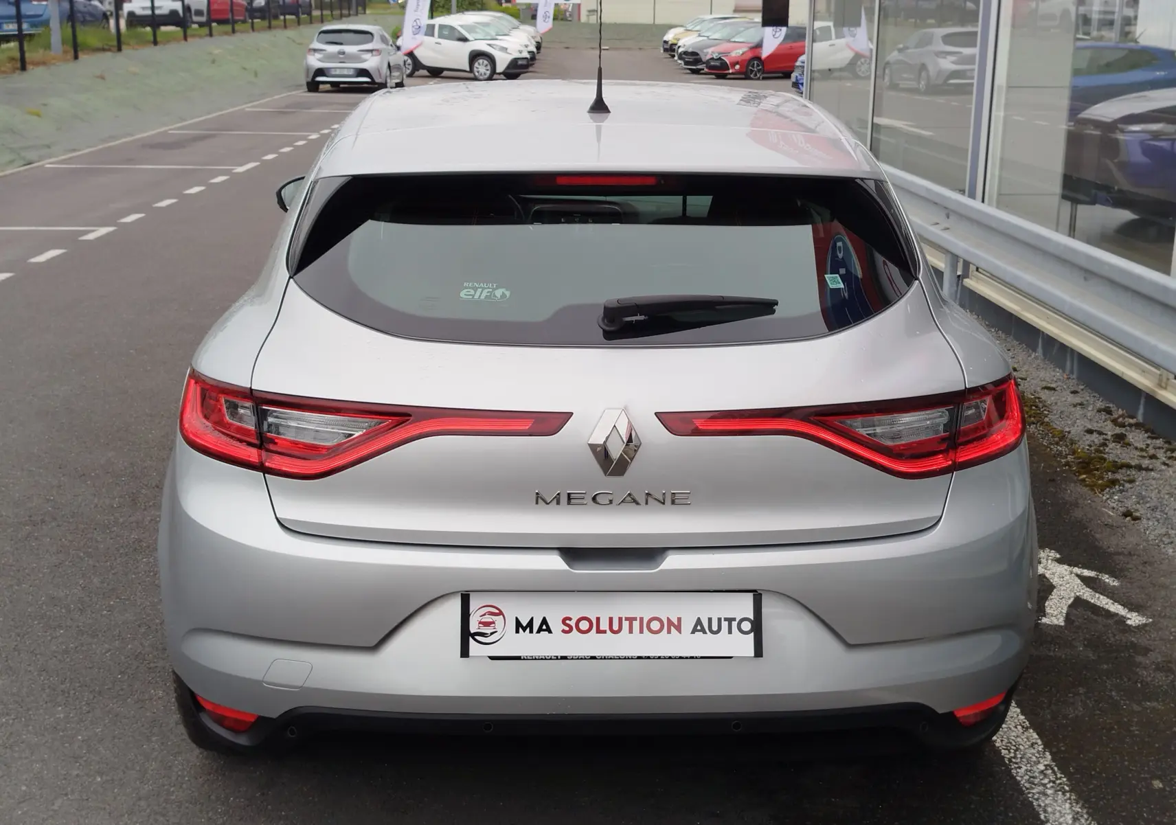 Vue arrière d'une Renault Mégane gris titanium de 2018, avec feux LED caractéristiques et logo central bien visible.