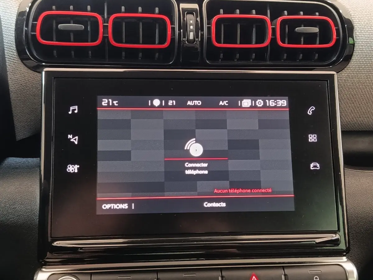 Vue rapprochée de l’écran tactile central et des aérateurs noirs avec contours rouges du tableau de bord beige du Citroën C3 Aircross.