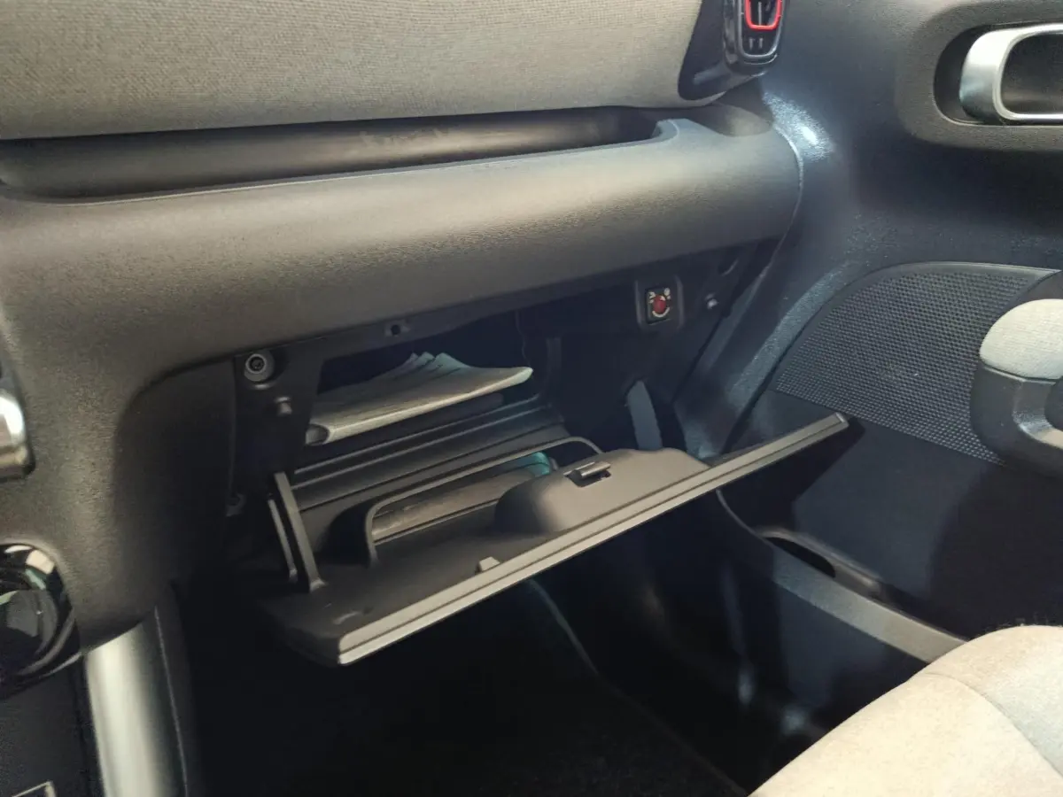 Vue intérieure côté passager du coffre à gants ouvert de la Citroën C3 Aircross beige, montrant son rangement et la texture du tableau de bord.