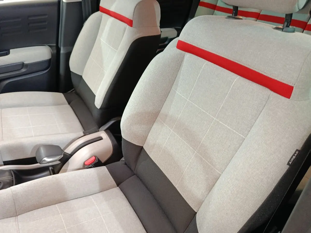Gros plan sur les sièges avant gris clair avec bande rouge et détails noirs de la Citroën C3 Aircross Shine 2021.