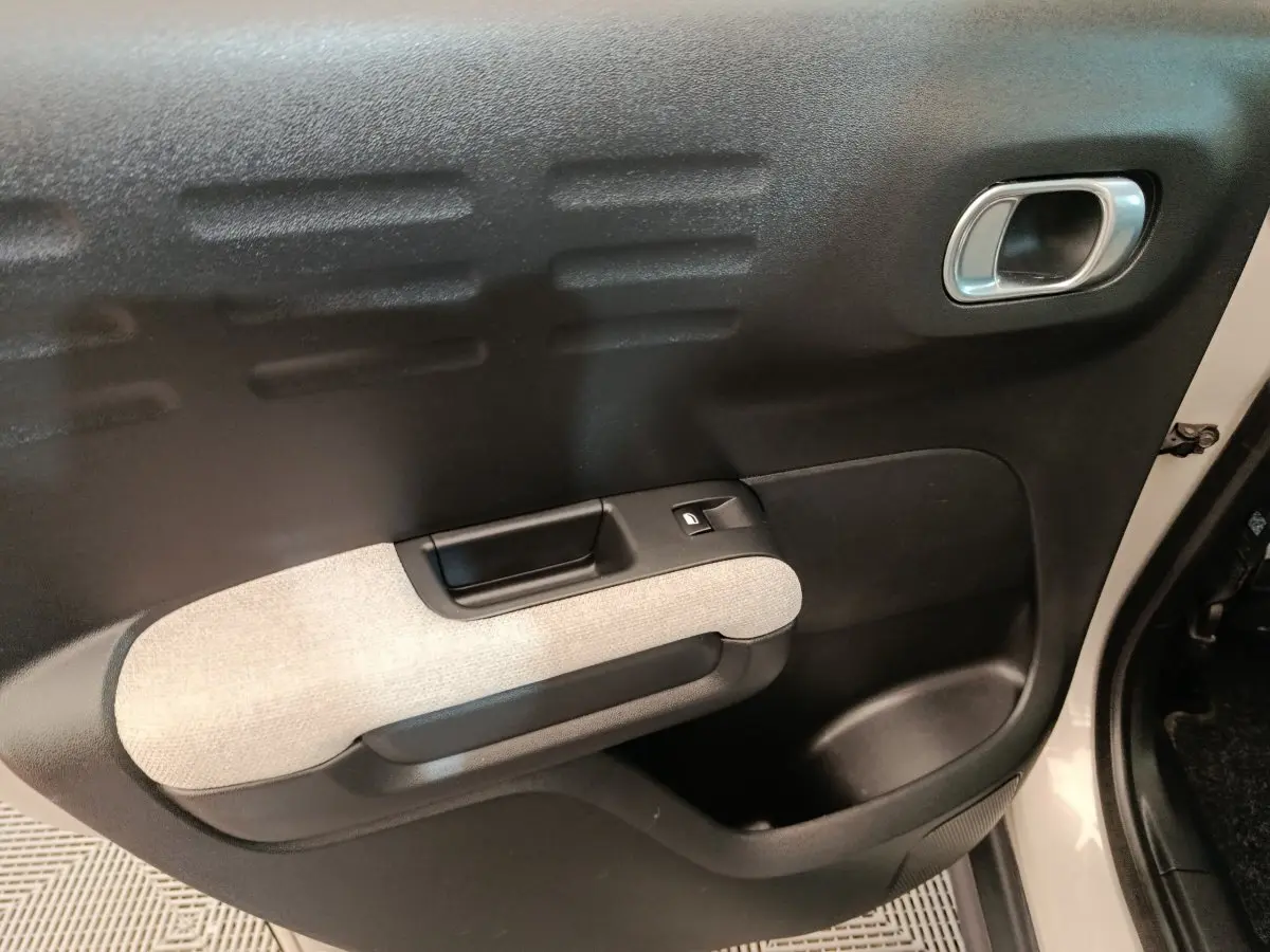 Détail de la porte avant droite beige et noire de la Citroën C3 Aircross 2021 avec poignée intégrée et bouton de vitre électrique.
