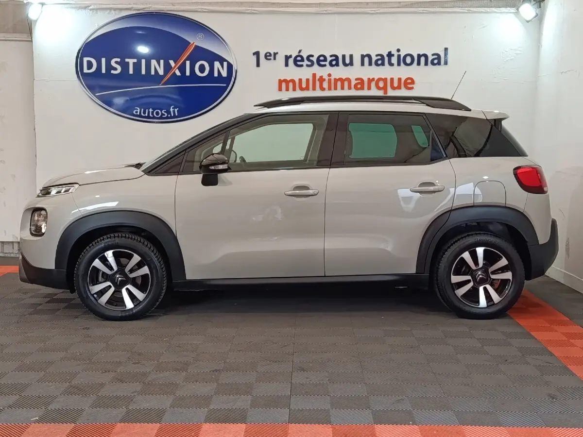 Vue de profil côté gauche d'un Citroën C3 Aircross beige 2021 avec toit noir et jantes bicolores.