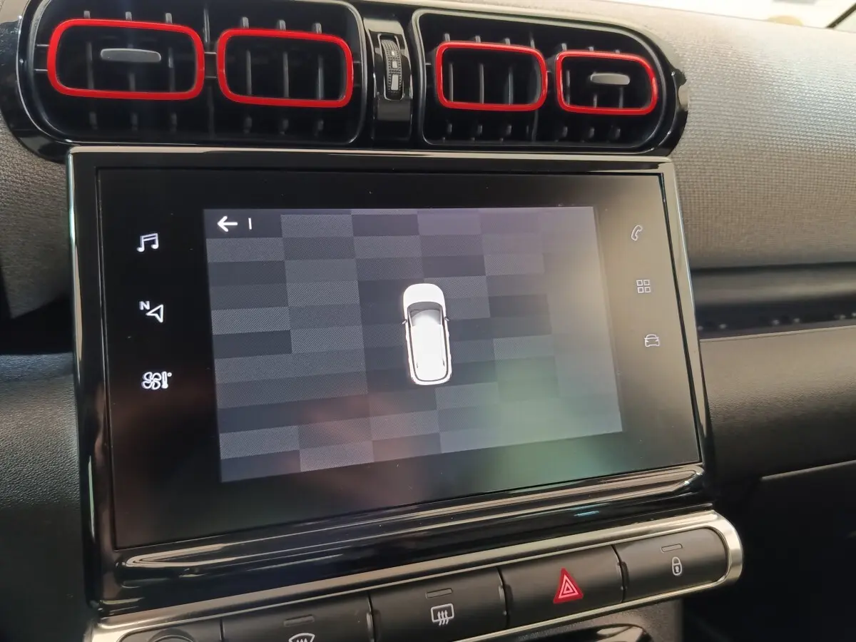 Vue rapprochée de l’écran tactile central et des aérateurs noirs avec contours rouges dans l’habitacle du Citroën C3 Aircross beige.