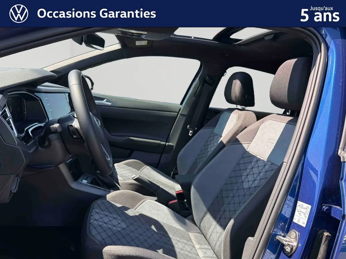 Vue intérieure côté conducteur du Volkswagen Taigo bleu 2025, sièges sport confort en tissu gris et noir.