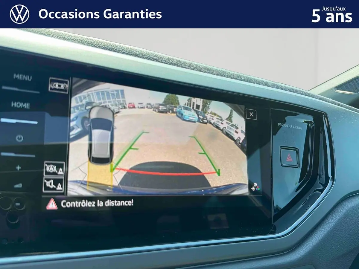 Écran tactile intérieur montrant la caméra de recul du Volkswagen Taigo bleu, avec aides au stationnement visibles.