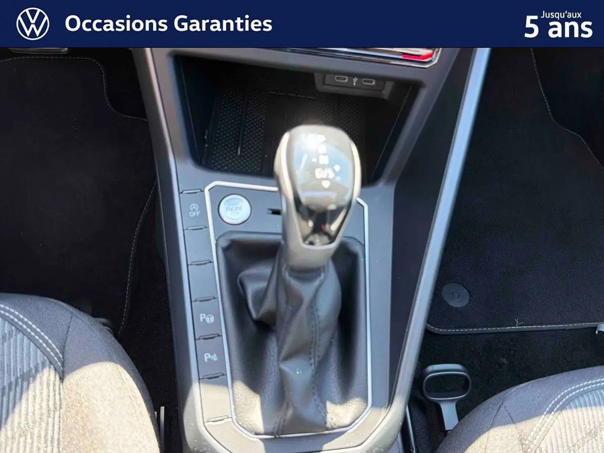 Gros plan sur la console centrale du Volkswagen Taigo bleu, mettant en valeur le levier de vitesse manuel et les commandes de stationnement.