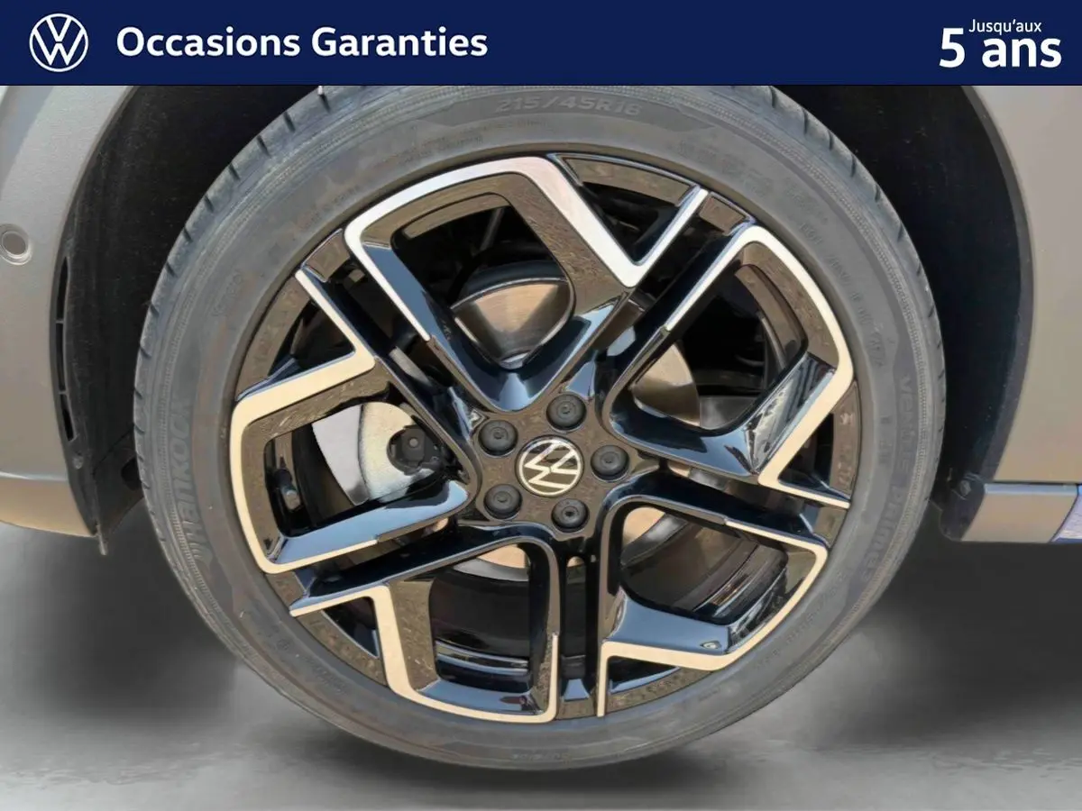 Gros plan sur la jante alliage noir et argent 18 pouces du Volkswagen Taigo bleu, avec logo VW au centre.