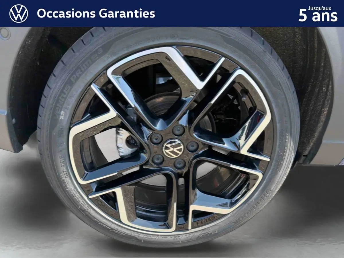 Gros plan sur la jante alliage noir et argent 18 pouces du Volkswagen Taigo bleu, avec logo VW central visible.
