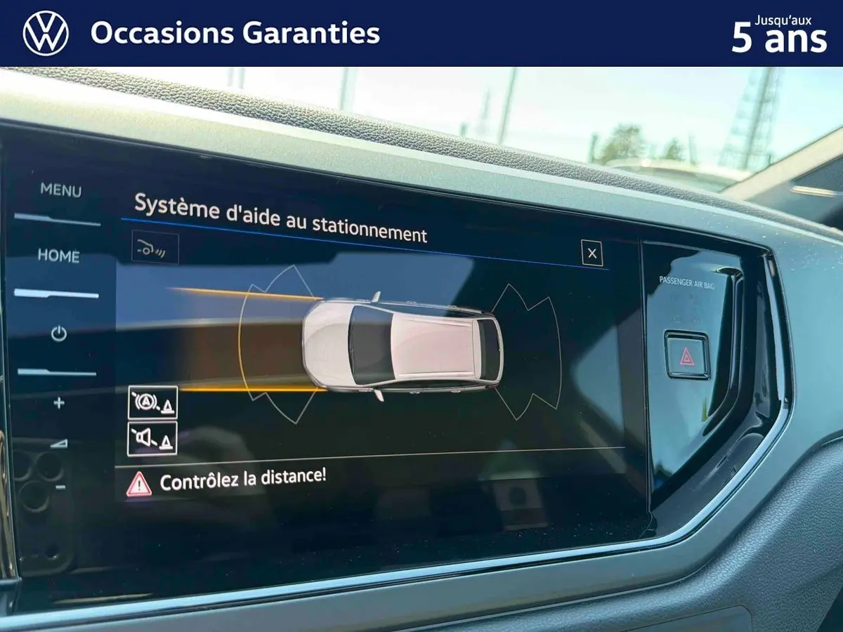 Écran tactile intérieur montrant l'aide au stationnement du Volkswagen Taigo bleu, vue de face côté conducteur.