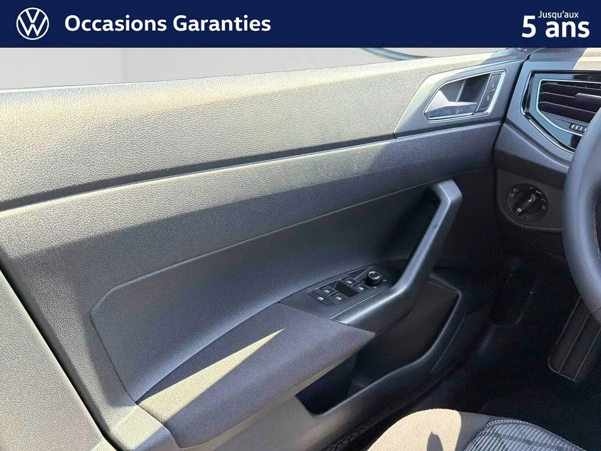 Détail de la porte avant gauche du Volkswagen Taigo bleu 2025, avec commandes des vitres et poignée intégrée.