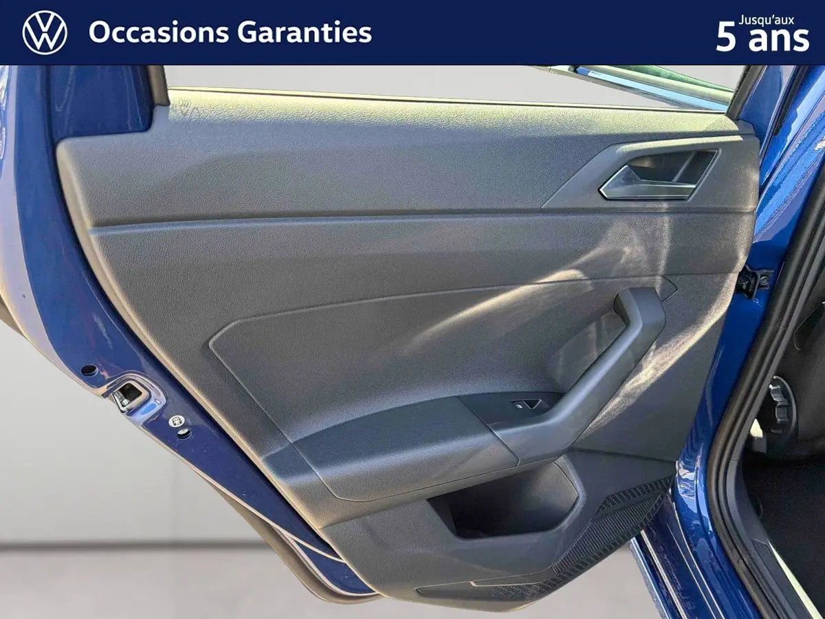Vue rapprochée de la porte arrière gauche bleu métallisé du Volkswagen Taigo, montrant la garniture intérieure noire.