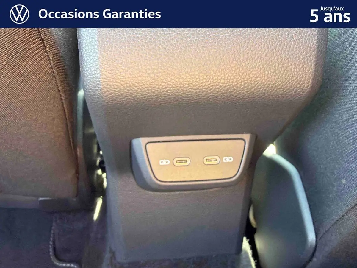 Gros plan sur la console centrale arrière du Volkswagen Taigo bleu, montrant deux ports USB-C pour recharge.