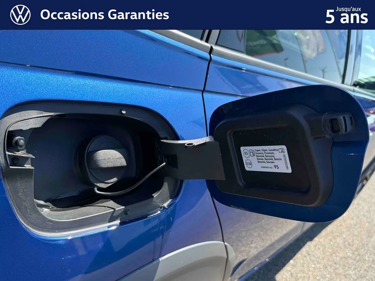 Détail de la trappe à carburant ouverte sur le côté gauche d’un Volkswagen Taigo bleu métallisé.