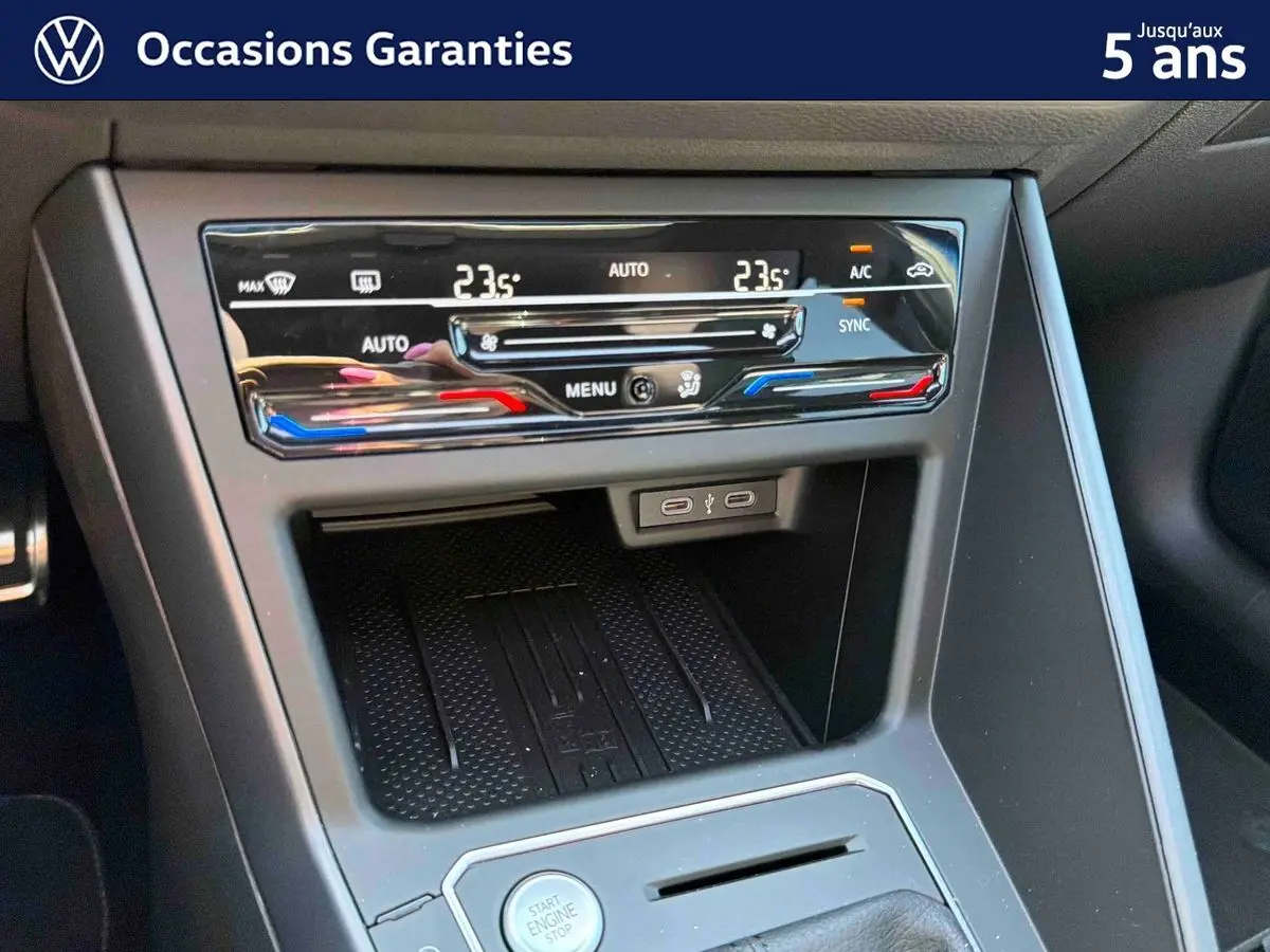 Détail de la console centrale du Volkswagen Taigo 2025, montrant la climatisation tactile bi-zone et la zone de recharge sans fil.