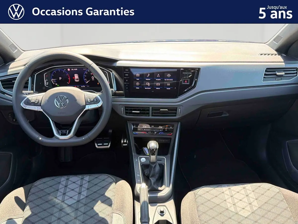 Vue intérieure avant du Volkswagen Taigo 2025 avec volant multifonctions, écran tactile et levier de vitesse manuel.