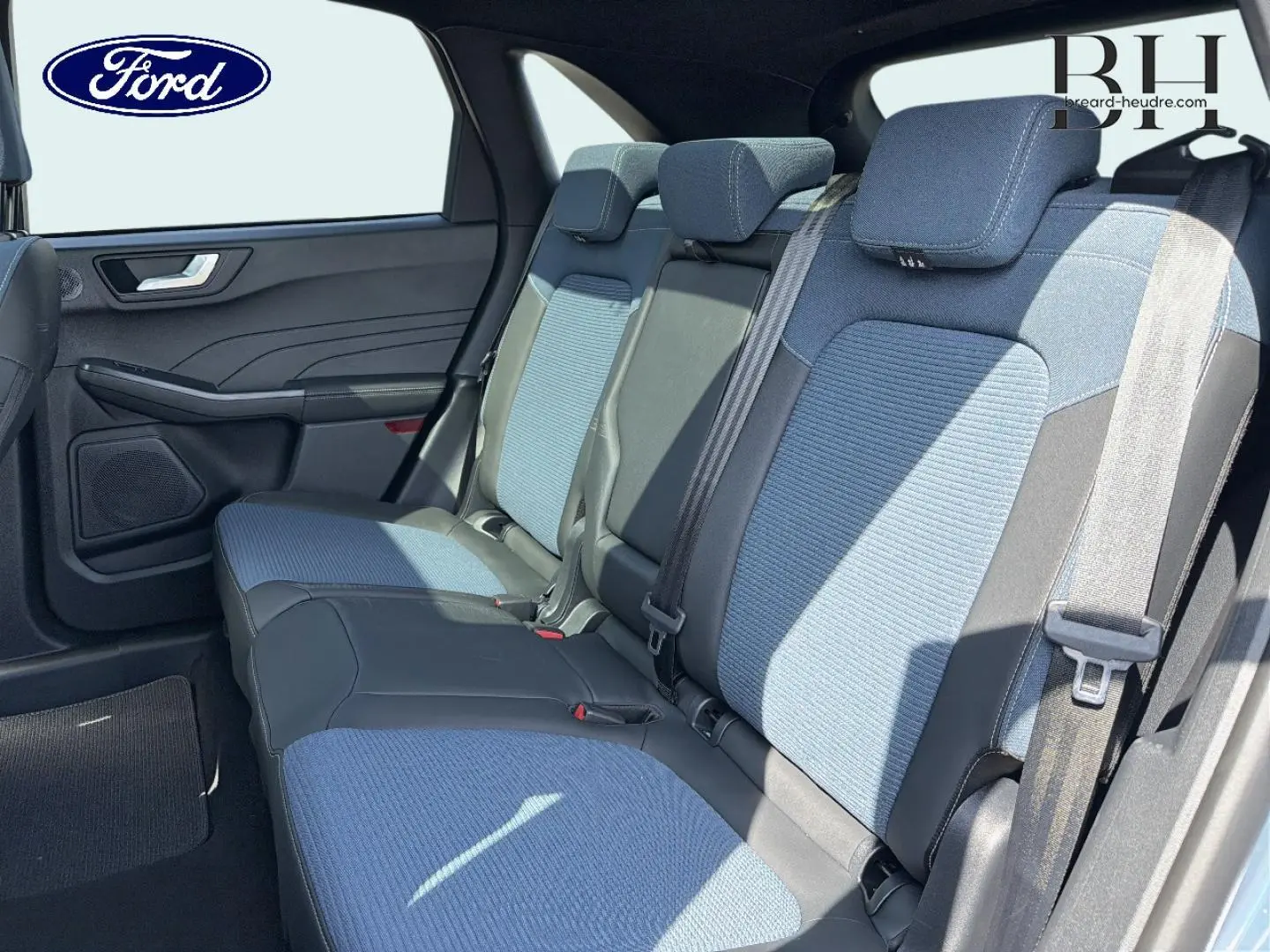 Vue latérale intérieure sur la banquette arrière bleu et noir du Ford Kuga 2026 avec ceintures et appuie-têtes.
