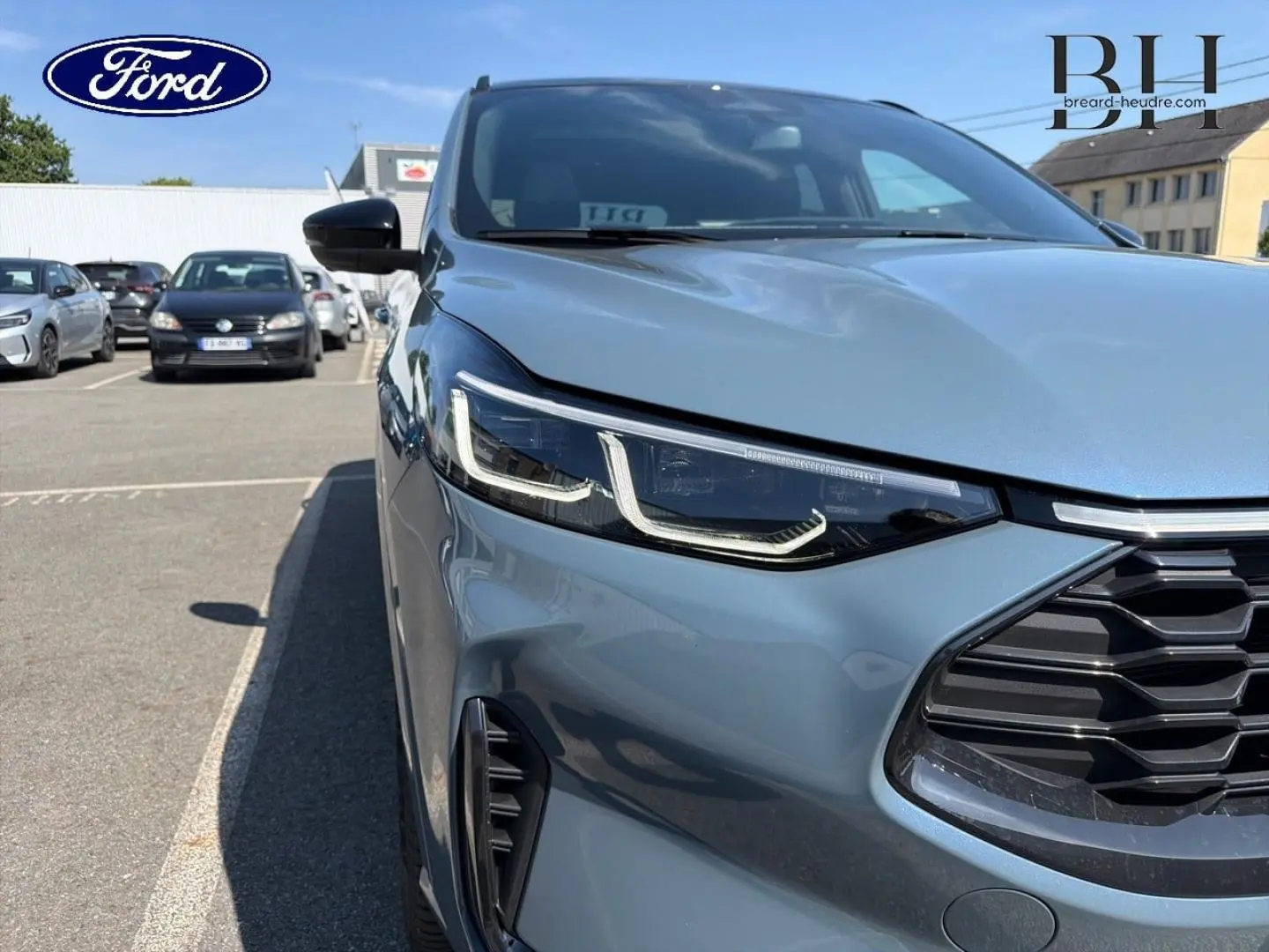 Gros plan sur l’avant droit du Ford Kuga bleu métallisé, mettant en valeur le phare LED et la calandre noire.