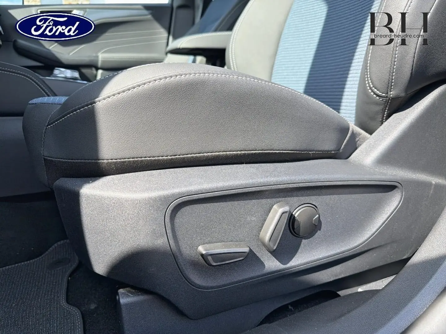 Gros plan sur les commandes de réglage électrique du siège conducteur gris du Ford Kuga 2026, intérieur lumineux.