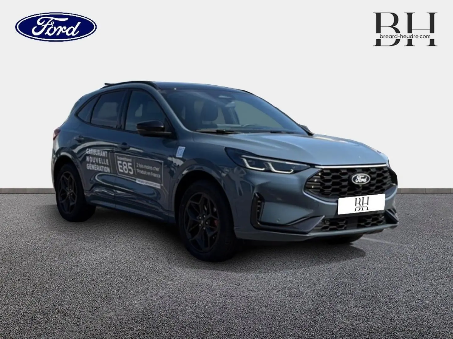 Ford Kuga bleu 3/4 avant droit avec toit panoramique et jantes noires, sur fond neutre.