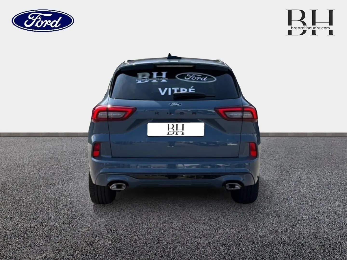 Vue arrière d'un Ford Kuga bleu métallisé 2026 avec double sortie d'échappement et toit panoramique visible.