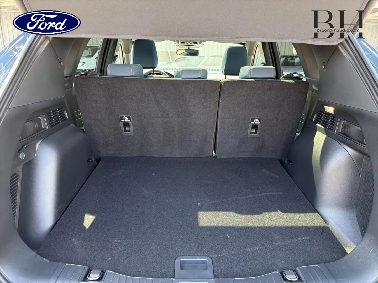 Coffre spacieux vu de l'arrière avec banquette arrière relevée d'un Ford Kuga bleu, intérieur noir.