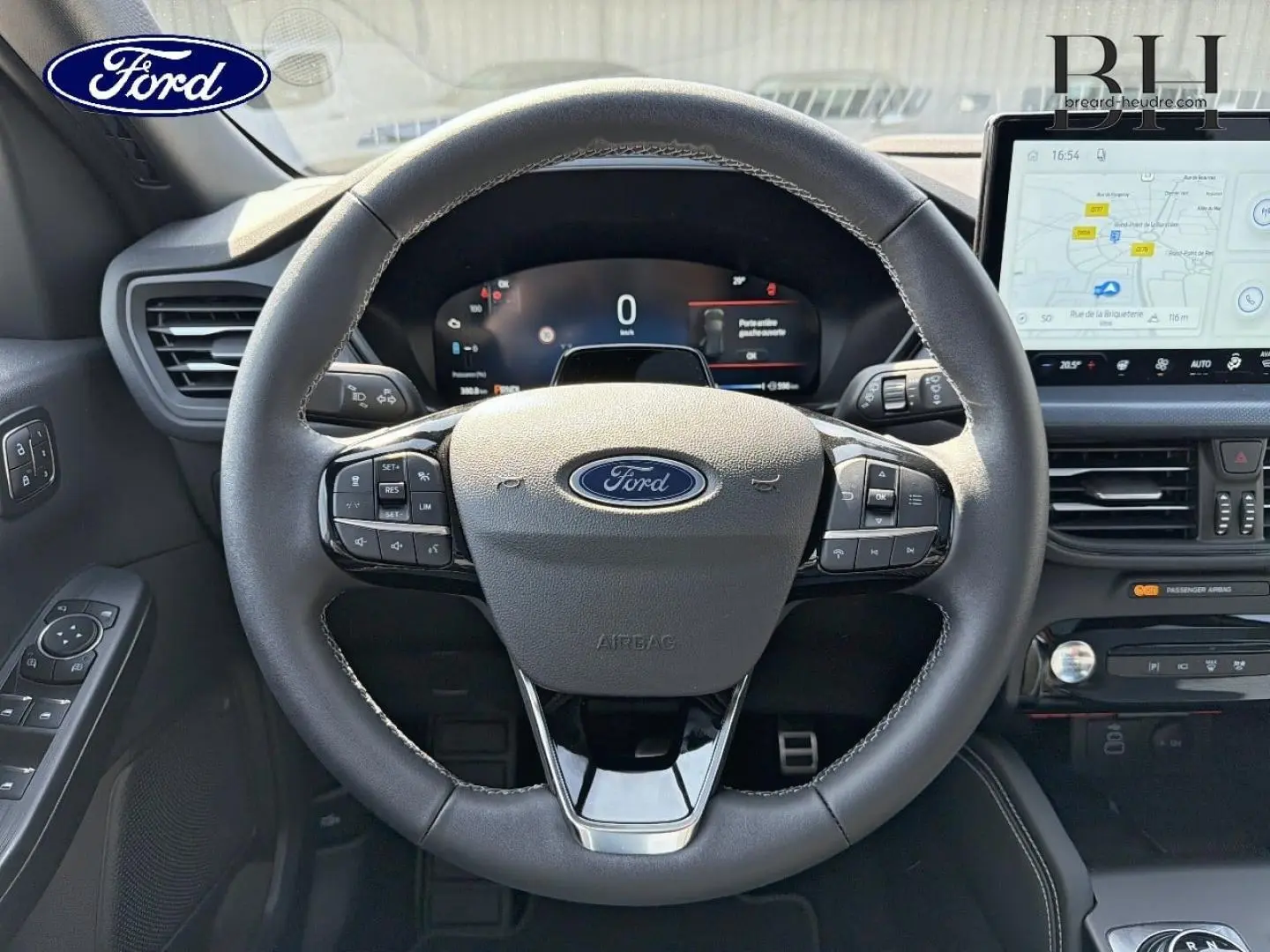 Vue intérieure centrée sur le volant noir multifonction du Ford Kuga 2026 avec écran tactile et tableau de bord numérique.