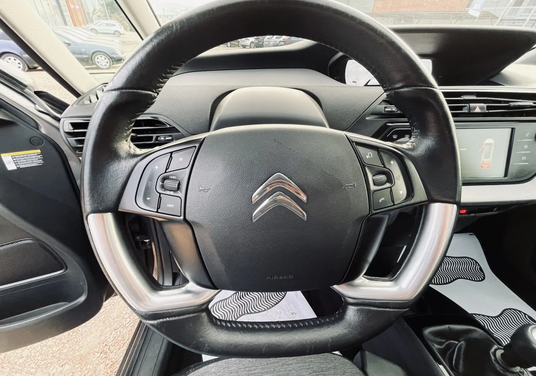 Vue rapprochée du volant cuir noir avec commandes intégrées du tableau de bord d'une Citroën C4 Picasso gris métal 2018.