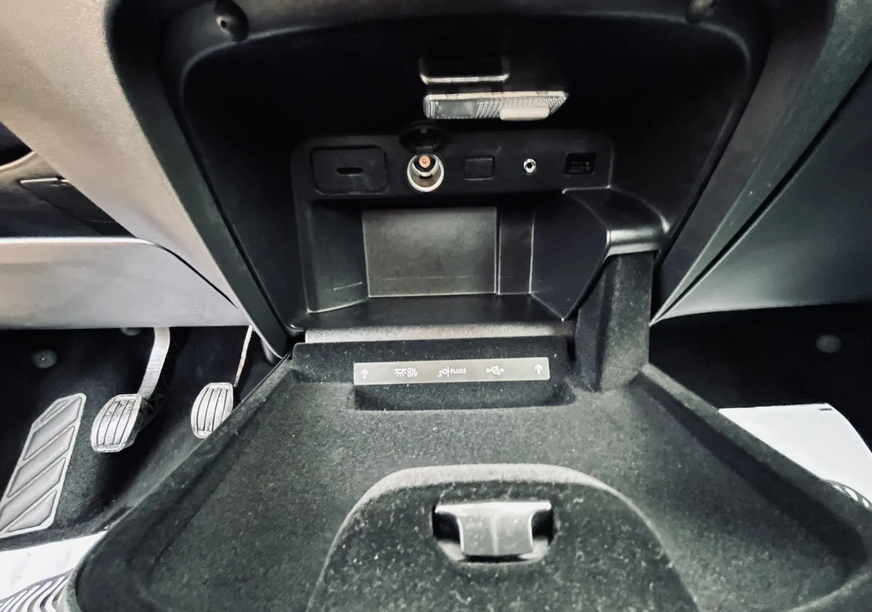 Gros plan sur la console centrale ouverte du Citroën C4 Picasso gris, montrant prises USB et allume-cigare.
