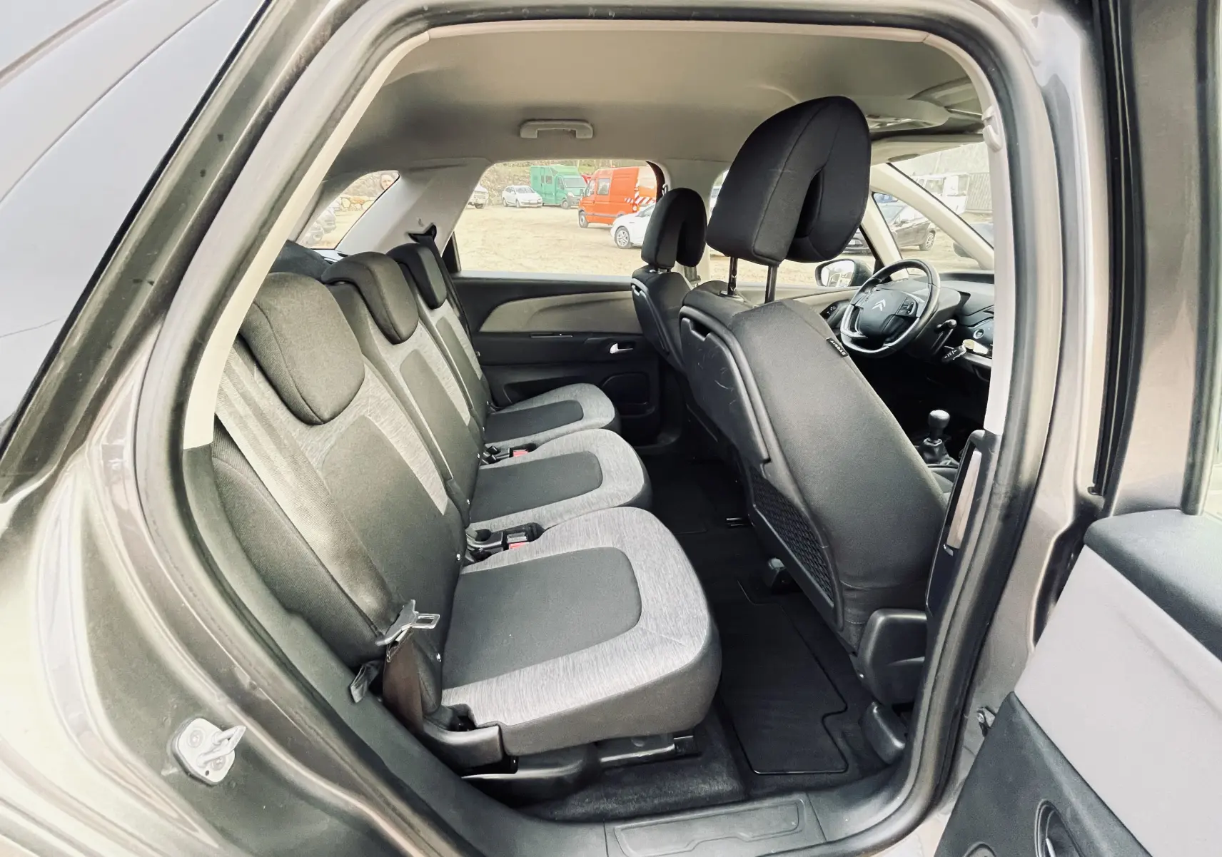 Vue intérieure côté droit du Citroën C4 Picasso gris, montrant les sièges arrière en tissu bicolore et le tableau de bord avant.