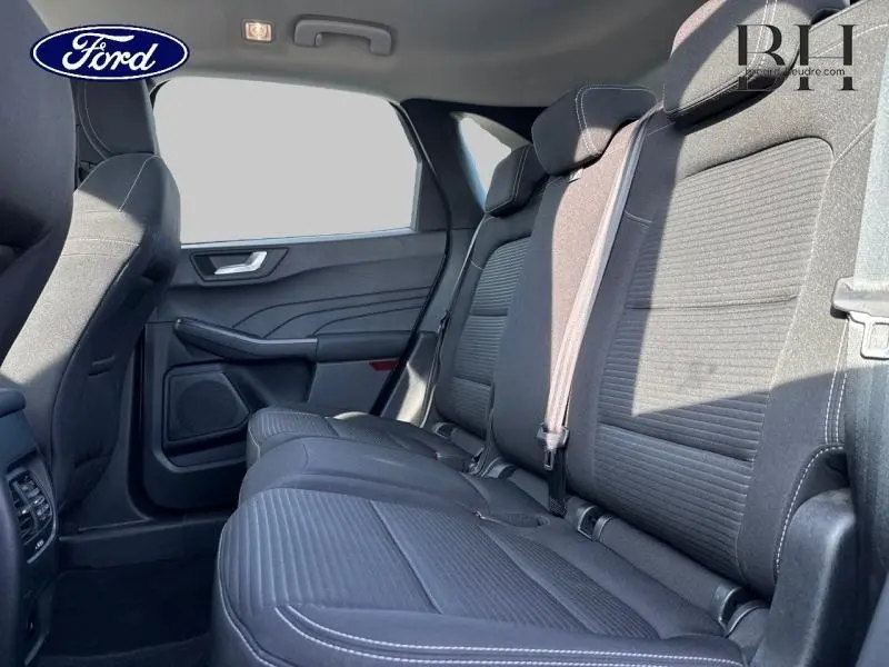 Vue latérale droite de l'habitacle arrière du Ford Kuga 2023 avec sièges tissu noir et ceintures de sécurité visibles.