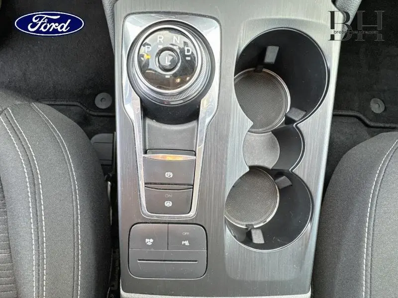 Vue plongeante sur la console centrale du Ford Kuga 2023 avec molette de boîte auto et porte-gobelets noirs.