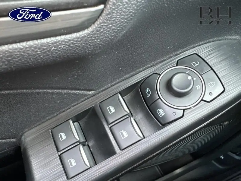 Gros plan sur les commandes de lève-vitres et rétroviseurs côté conducteur du Ford Kuga 2023 finition Titanium.