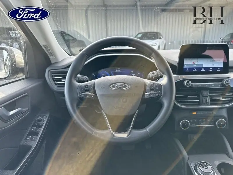 Vue intérieure du tableau de bord du Ford Kuga 2023, volant cuir multifonction et écran tactile central visible.