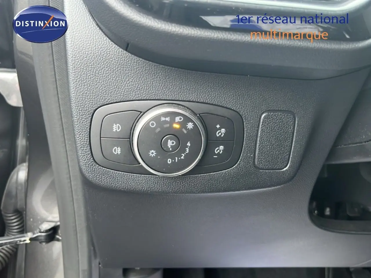 Gros plan sur le bouton de réglage des phares du tableau de bord d'une Ford Puma gris magnetic metal, version 2024.
