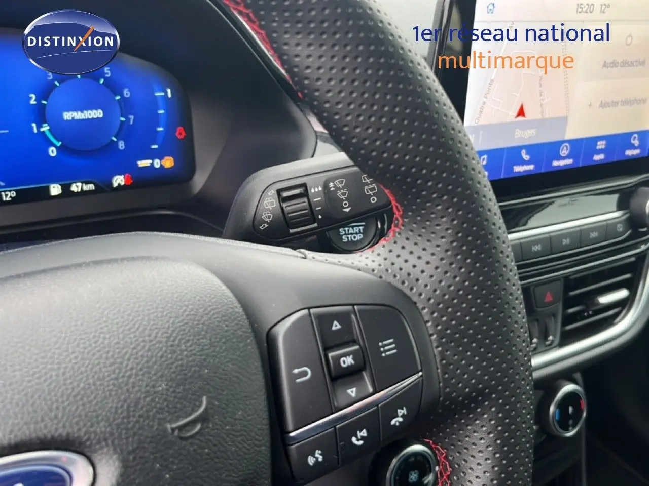 Vue rapprochée du volant perforé avec surpiqûres rouges et tableau de bord numérique du Ford Puma gris Magnetic Metal 2024.