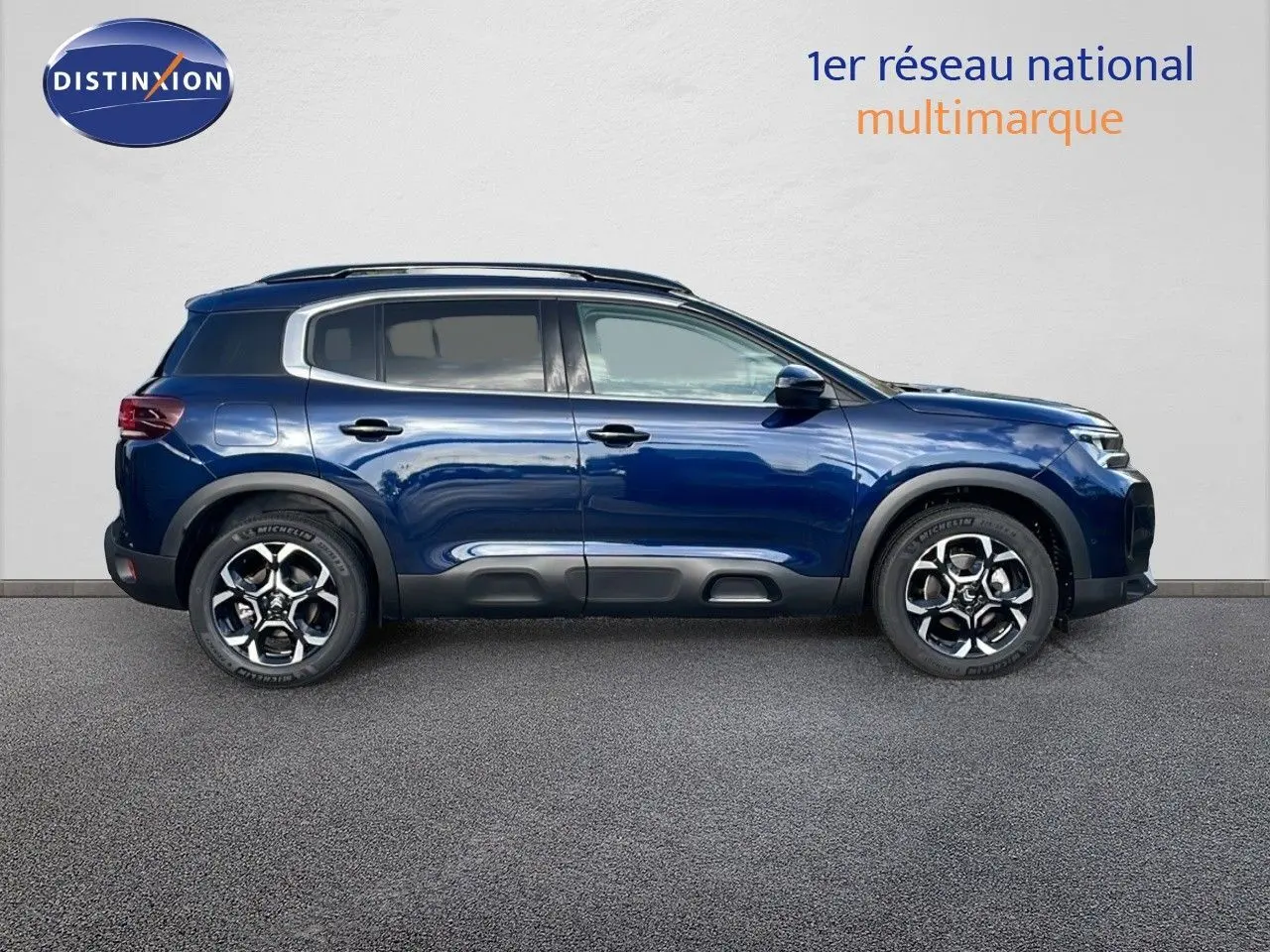 Profil latéral droit d'un Citroën C5 Aircross 2025 bleu eclipse métal avec jantes alliage bicolores et protections noires.