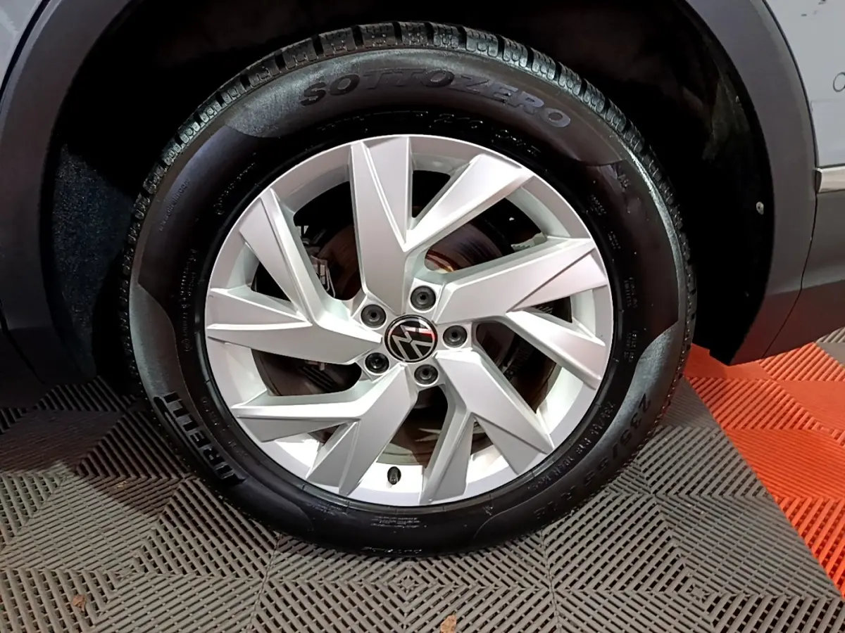 Gros plan sur la roue avant droite du Volkswagen Tiguan gris foncé, jante alliage argentée et pneu Pirelli Sottozero.