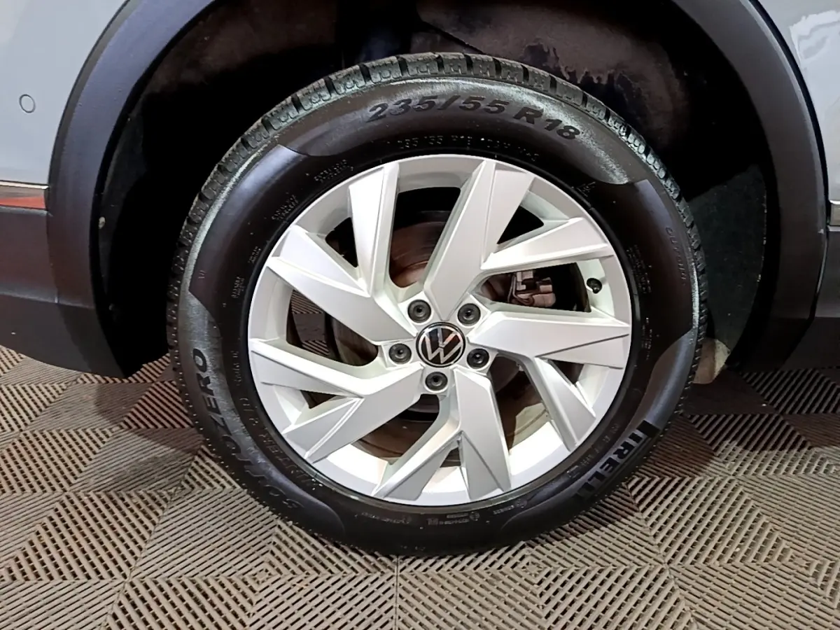 Gros plan sur la roue avant droite du Volkswagen Tiguan gris foncé avec jante alliage à design moderne.