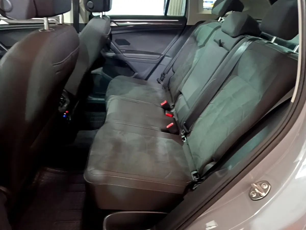 Vue latérale intérieure des sièges arrière gris foncé du Volkswagen Tiguan 2021, montrant les ceintures et appuie-têtes.