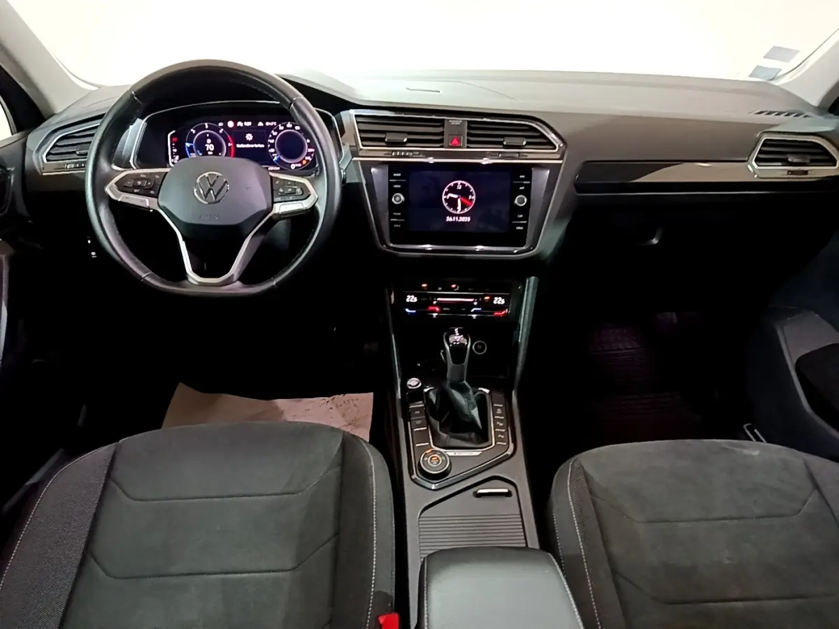 Vue intérieure avant du Volkswagen Tiguan 2.0 TDI 2021, tableau de bord noir avec écran tactile et volant cuir multifonctions.