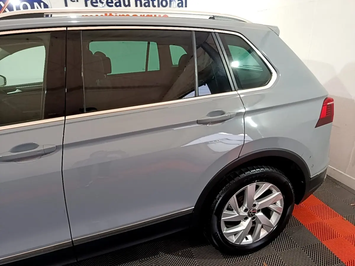 Vue latérale côté droit d'un Volkswagen Tiguan gris foncé avec jantes alliage et vitres teintées.